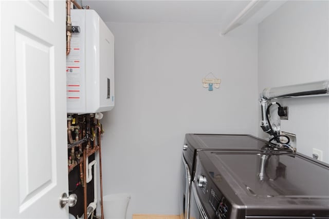 laundry room featuring laundry area, water heater, and washing machine and clothes dryer