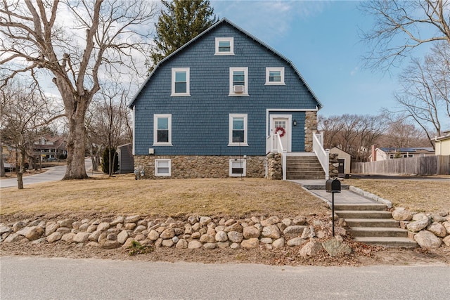 view of front of house featuring fence, a front lawn, and a gambrel roof