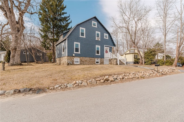 view of side of home featuring a lawn and a gambrel roof