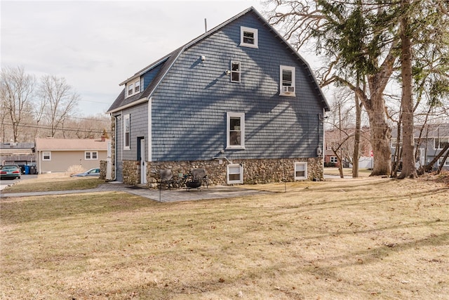 view of side of home featuring a yard, a patio area, and a gambrel roof