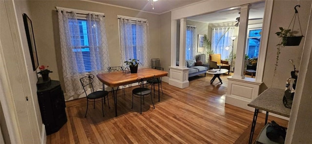 dining room with crown molding, light wood-style floors, and ornate columns