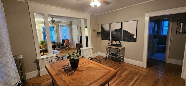 living area with decorative columns, baseboards, a ceiling fan, wood finished floors, and crown molding