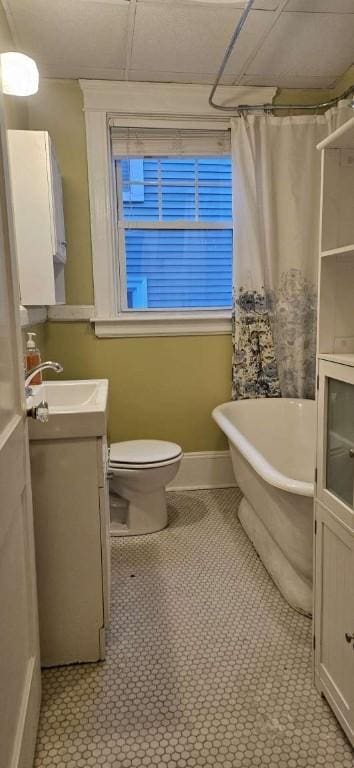 bathroom featuring toilet, vanity, baseboards, a soaking tub, and a shower with curtain