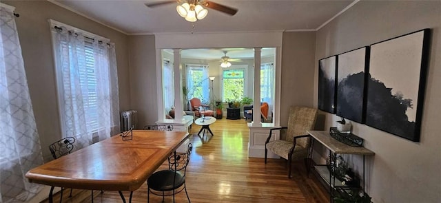 dining area with radiator heating unit, ceiling fan, ornate columns, and wood finished floors