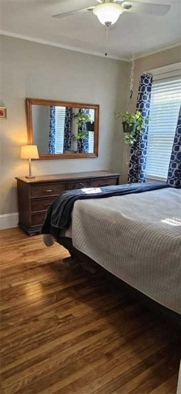 bedroom featuring baseboards, ornamental molding, ceiling fan, and hardwood / wood-style flooring