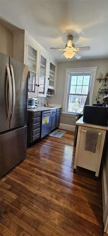 kitchen with ceiling fan, appliances with stainless steel finishes, light countertops, baseboards, and dark wood-style floors