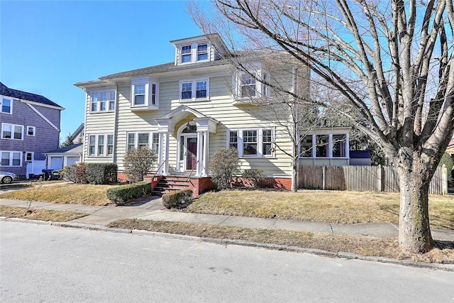 american foursquare style home with fence and a front lawn