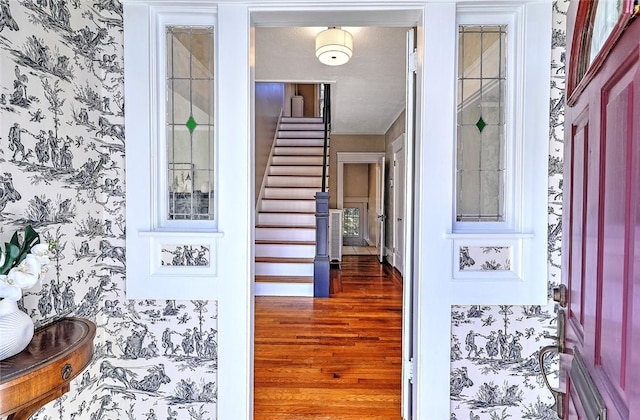 interior space featuring baseboards, stairway, wood finished floors, and wallpapered walls