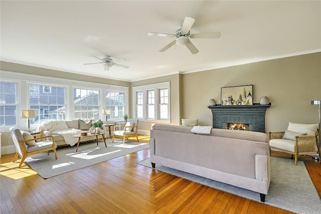 living area with baseboards, a fireplace, hardwood / wood-style flooring, and crown molding