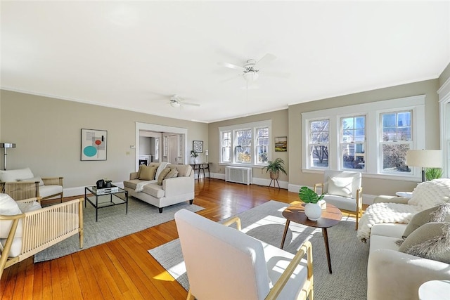 living room with baseboards, radiator heating unit, wood-type flooring, and crown molding