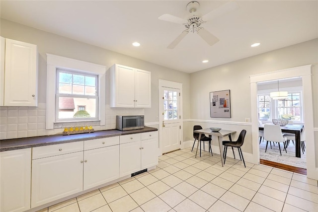 kitchen featuring stainless steel microwave, dark countertops, and decorative backsplash