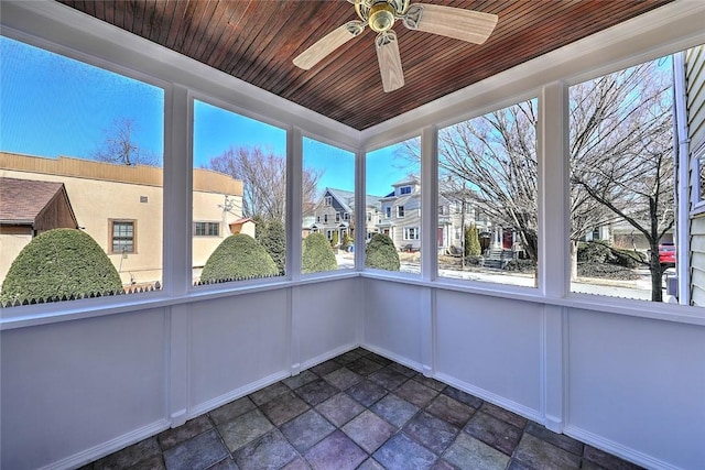 unfurnished sunroom featuring a ceiling fan, a residential view, and wood ceiling