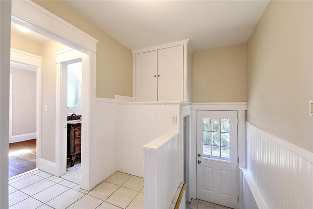 entryway with a wainscoted wall and light tile patterned flooring