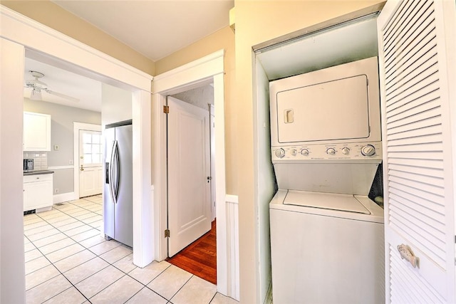 laundry area featuring stacked washer and dryer, laundry area, ceiling fan, and light tile patterned floors