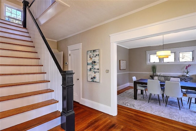 staircase with crown molding, baseboards, and wood finished floors