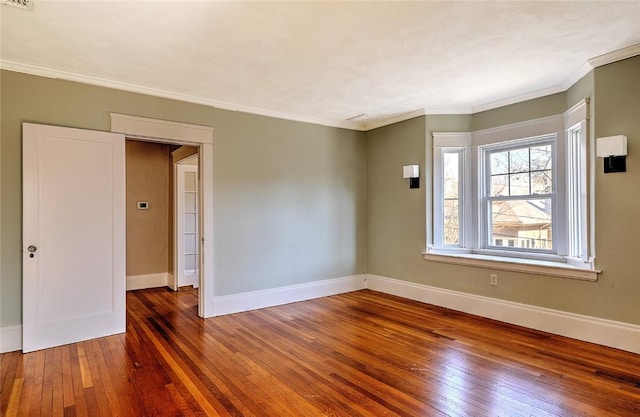 empty room featuring hardwood / wood-style flooring, baseboards, and ornamental molding