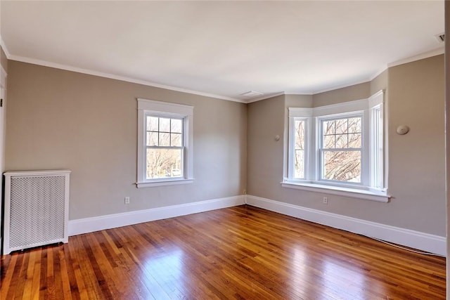 unfurnished room featuring wood-type flooring, crown molding, and baseboards