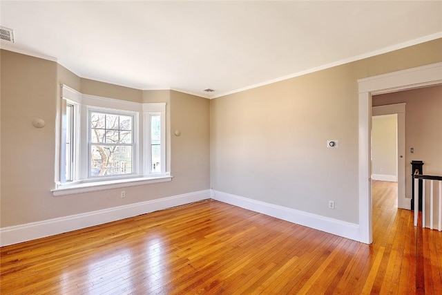 empty room with light wood-type flooring, baseboards, and ornamental molding