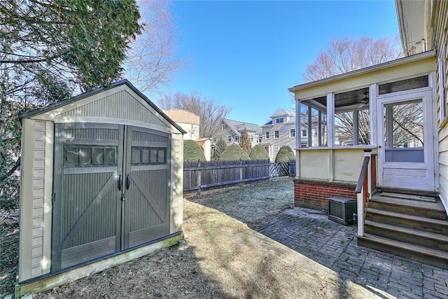 view of shed featuring entry steps, a sunroom, and a fenced backyard