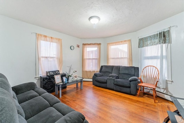 living room featuring a baseboard radiator, a textured ceiling, and light wood finished floors