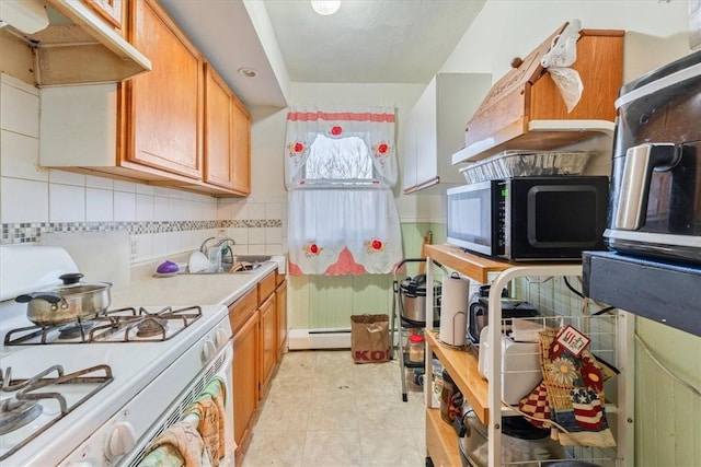 kitchen with light countertops, backsplash, baseboard heating, white range with gas stovetop, and under cabinet range hood