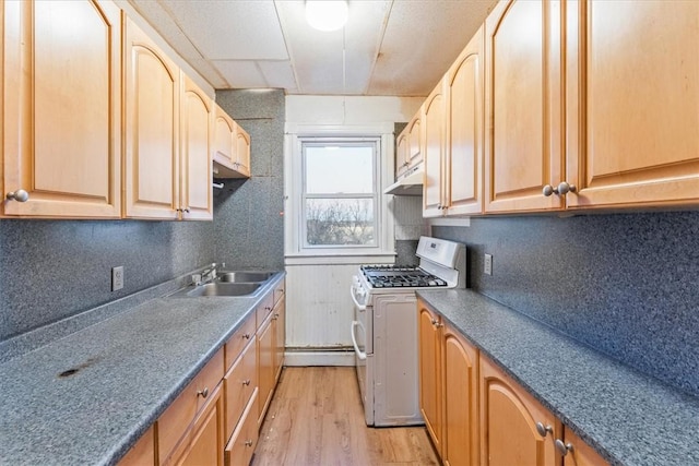 kitchen featuring under cabinet range hood, a sink, white range with gas cooktop, decorative backsplash, and light wood finished floors