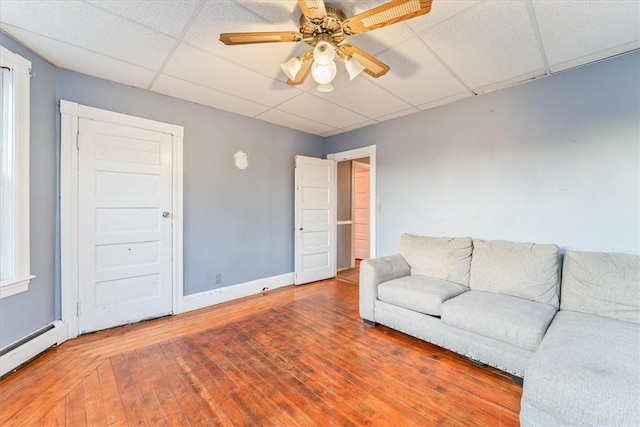 living room with baseboards, a ceiling fan, a baseboard radiator, hardwood / wood-style floors, and a paneled ceiling