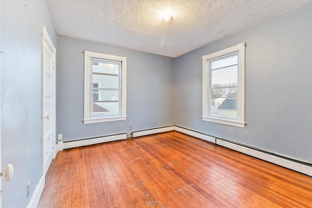 spare room with a baseboard heating unit, wood-type flooring, and a textured ceiling