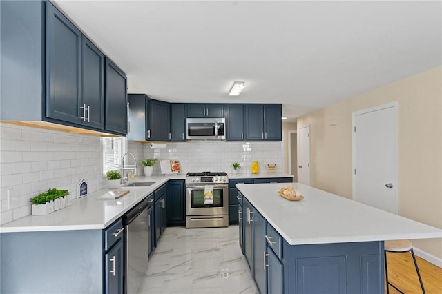 kitchen with a sink, a kitchen island, marble finish floor, appliances with stainless steel finishes, and light countertops