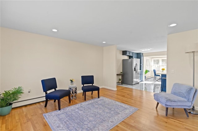 living area featuring light wood-style floors, baseboards, baseboard heating, and recessed lighting