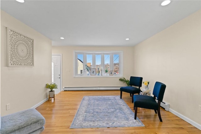 sitting room with a baseboard radiator, light wood-style flooring, and baseboards