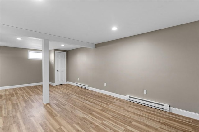 below grade area with light wood-type flooring, baseboards, baseboard heating, and recessed lighting