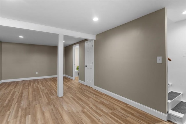 finished below grade area with light wood-style flooring, baseboards, and stairs