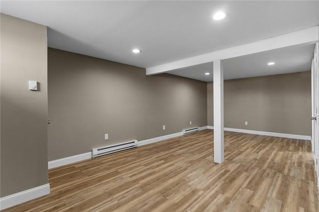 finished below grade area with a baseboard heating unit, recessed lighting, baseboards, and light wood finished floors