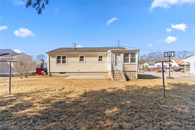 rear view of house with entry steps, a yard, and crawl space