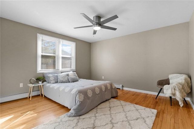 bedroom featuring ceiling fan, baseboard heating, hardwood / wood-style flooring, and baseboards