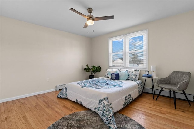 bedroom with light wood finished floors, baseboards, baseboard heating, and a ceiling fan