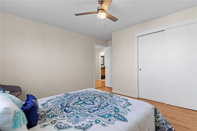 bedroom featuring light wood-type flooring, ceiling fan, baseboards, and a closet