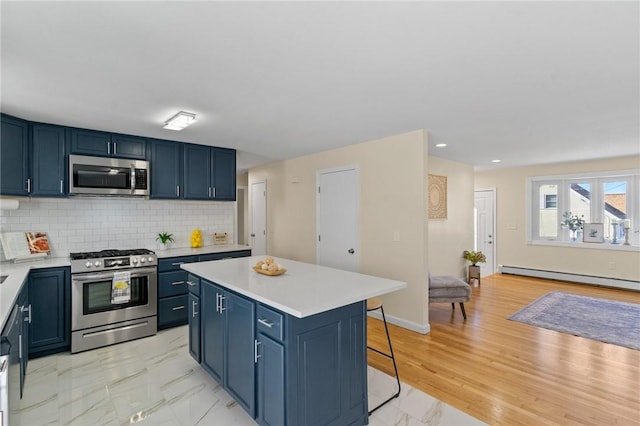 kitchen with stainless steel appliances, a baseboard radiator, marble finish floor, and blue cabinets