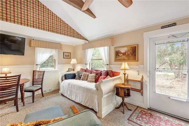 bedroom featuring access to exterior, wainscoting, vaulted ceiling with beams, and multiple windows