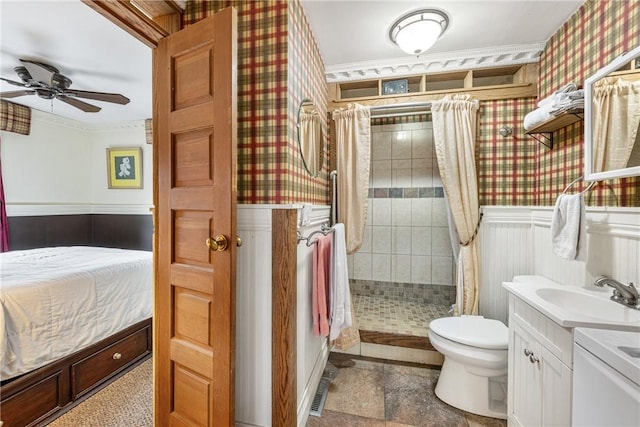 full bathroom featuring ceiling fan, toilet, a wainscoted wall, a stall shower, and wallpapered walls