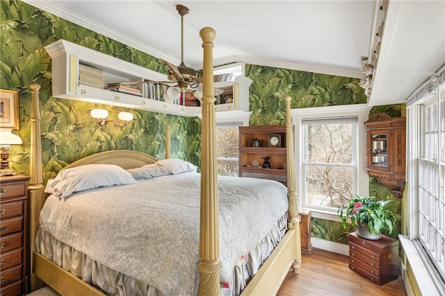 bedroom with wood finished floors, crown molding, and wallpapered walls