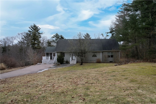 ranch-style home with aphalt driveway, entry steps, and a front yard