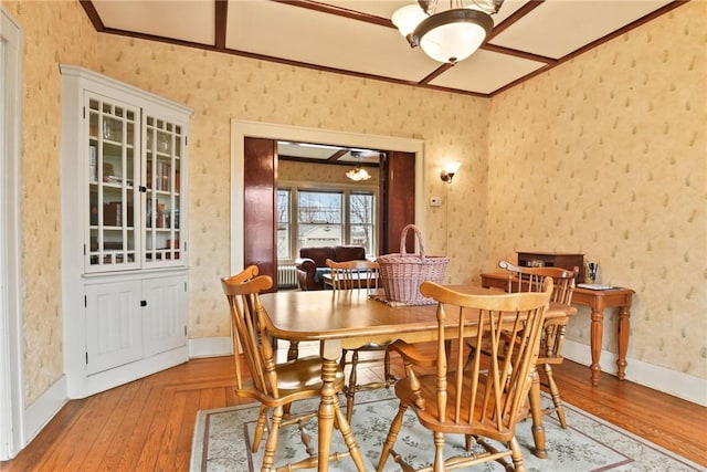 dining room featuring wallpapered walls, baseboards, wood finished floors, and ornamental molding