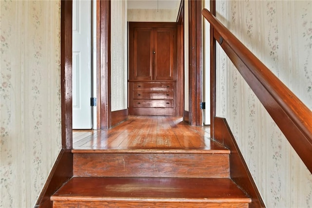 stairs featuring hardwood / wood-style floors and wallpapered walls