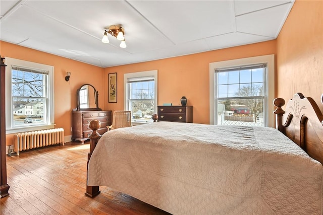 bedroom with baseboards, hardwood / wood-style floors, and radiator heating unit