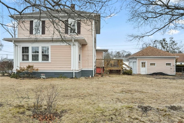 rear view of house with a chimney, an outbuilding, and a wooden deck