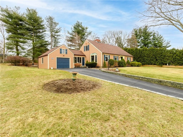 view of front facade featuring aphalt driveway, a front yard, a chimney, and an attached garage