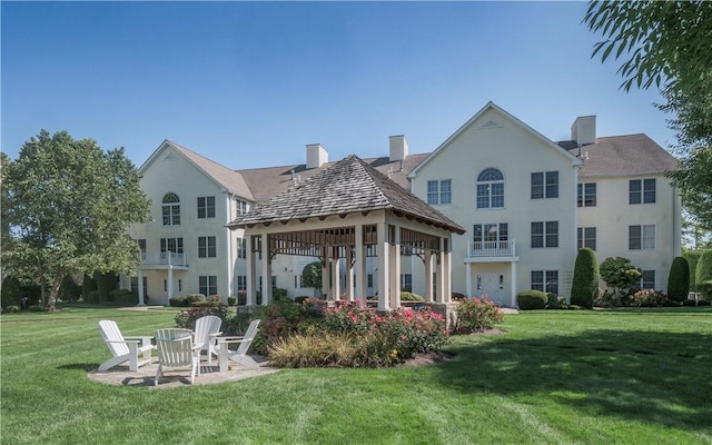 rear view of property featuring a gazebo, a lawn, and a patio