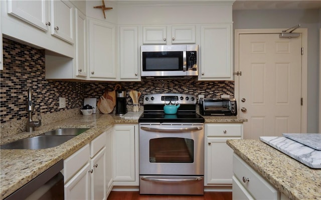 kitchen with stainless steel appliances, white cabinetry, a sink, and decorative backsplash